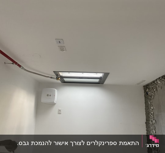 צינור כיבוי אש אדום מותקן על תקרה לבנה
